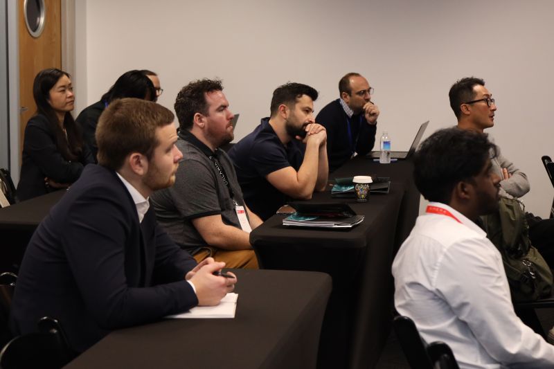 SmallSat Symposium attendees listening to a presentation in a meeting room.